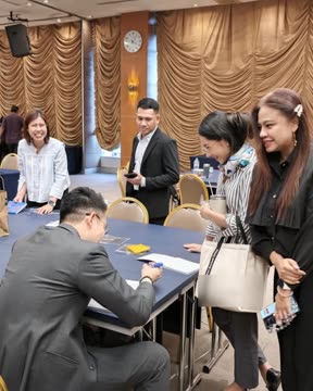 อาจารย์ภูมินั่งเซ็นชื่อให้ผู้เข้าร่วมที่ยืนรออยู่รอบโต๊ะหลังจบการอบรม