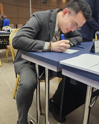 อาจารย์ภูมินั่งเขียนบนกระดาษที่โต๊ะในห้องอบรม